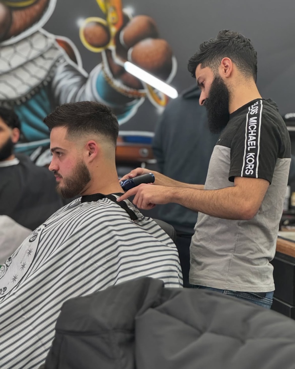 Burst fade with a curly top in front of the Slick Fades bear mural